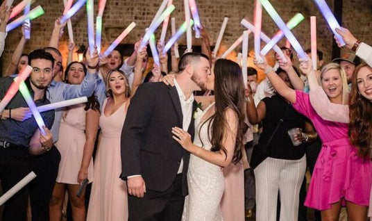 Led foam sticks at a wedding celebration with a married couple kissing