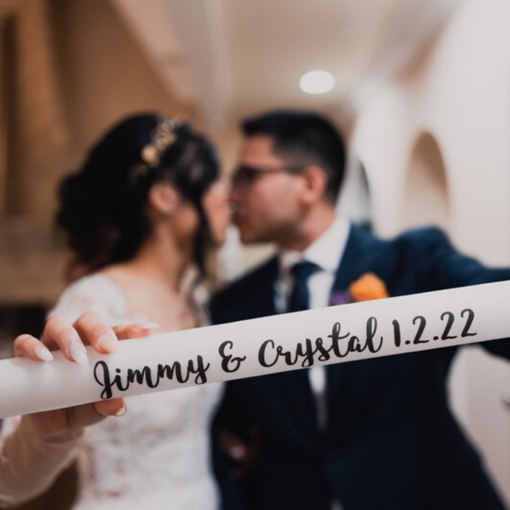a bride and groom kissing while holding a sign